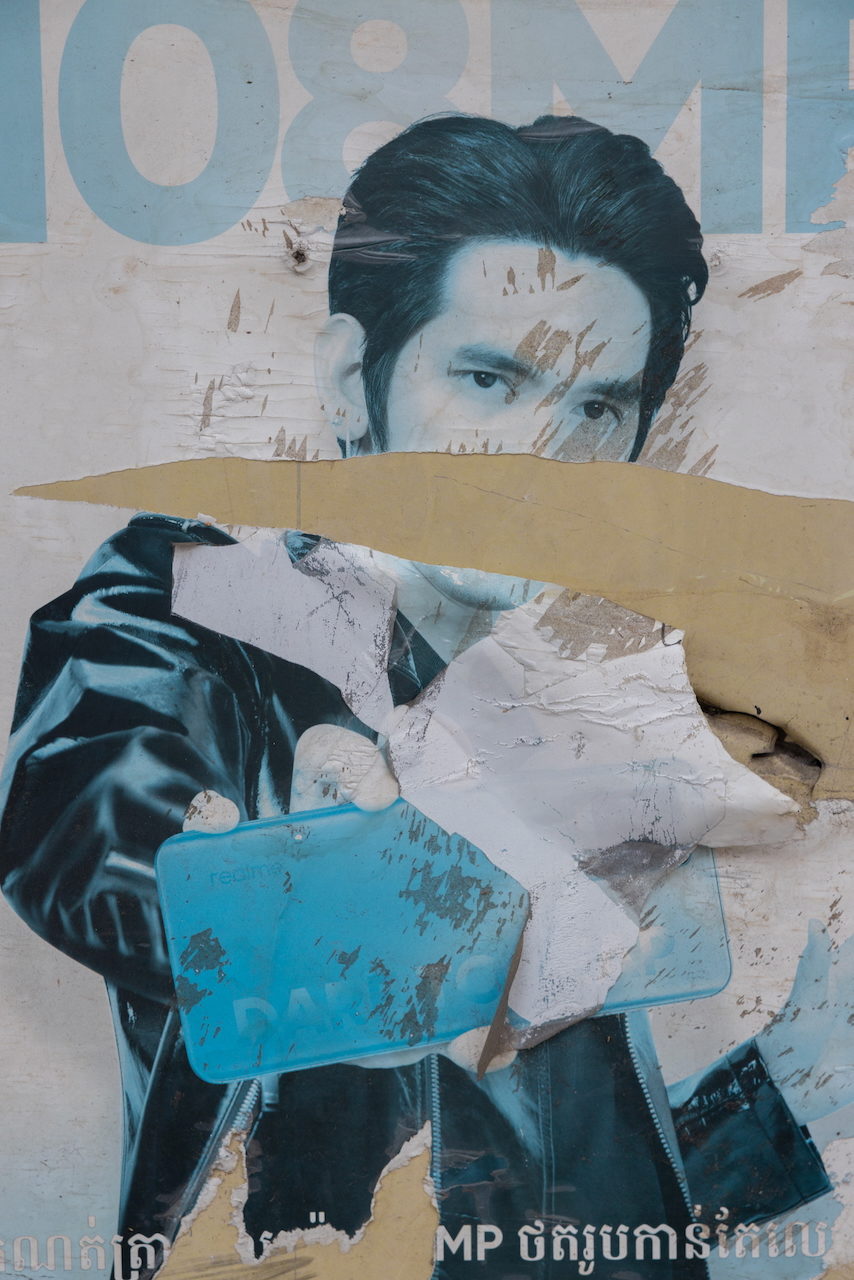 A torn billboard of a face peeling away from a wall.