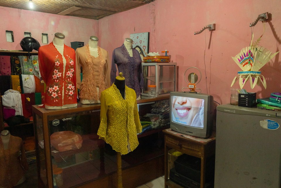 A tailor's shop of dressed mannequins with a television in the corner.