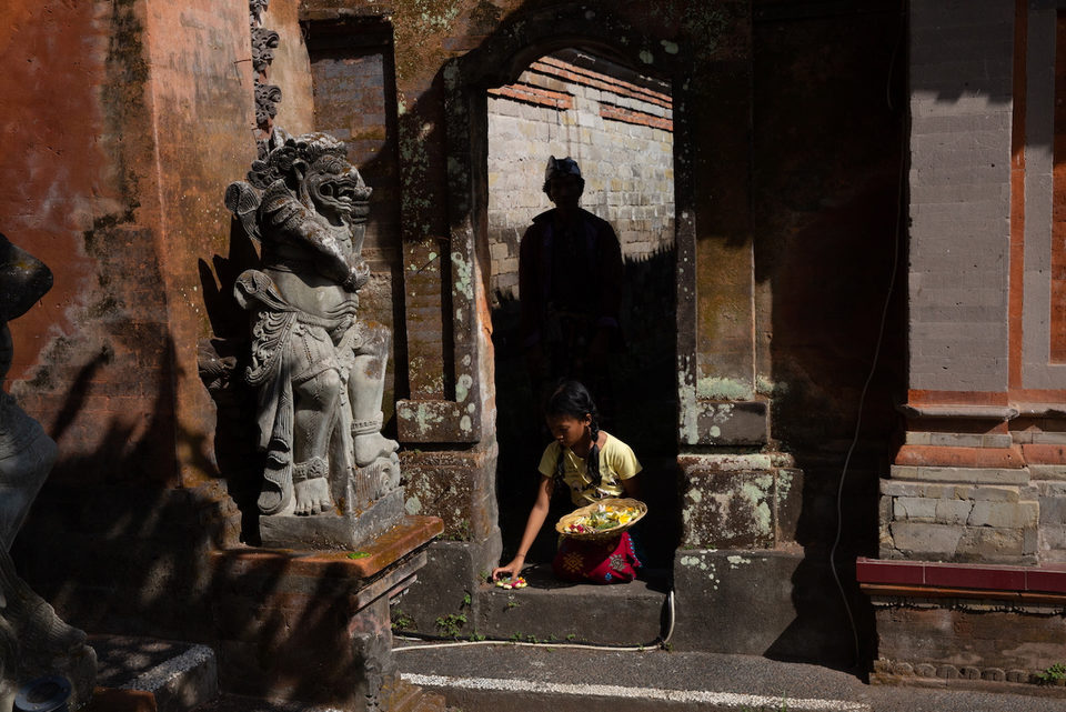 A girl carries an offering through a carved stone temple gateway.