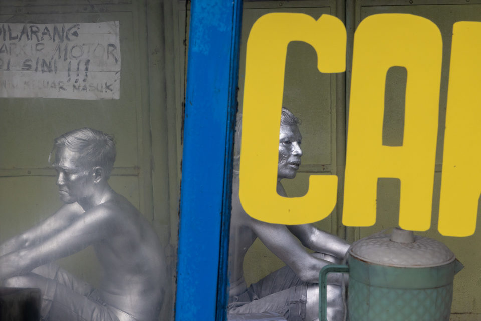 Yellow lettering on blue framing, silver-painted figures beyond the glass.