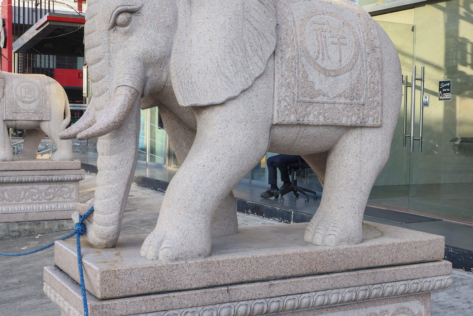 A carved stone elephant on a street corner.