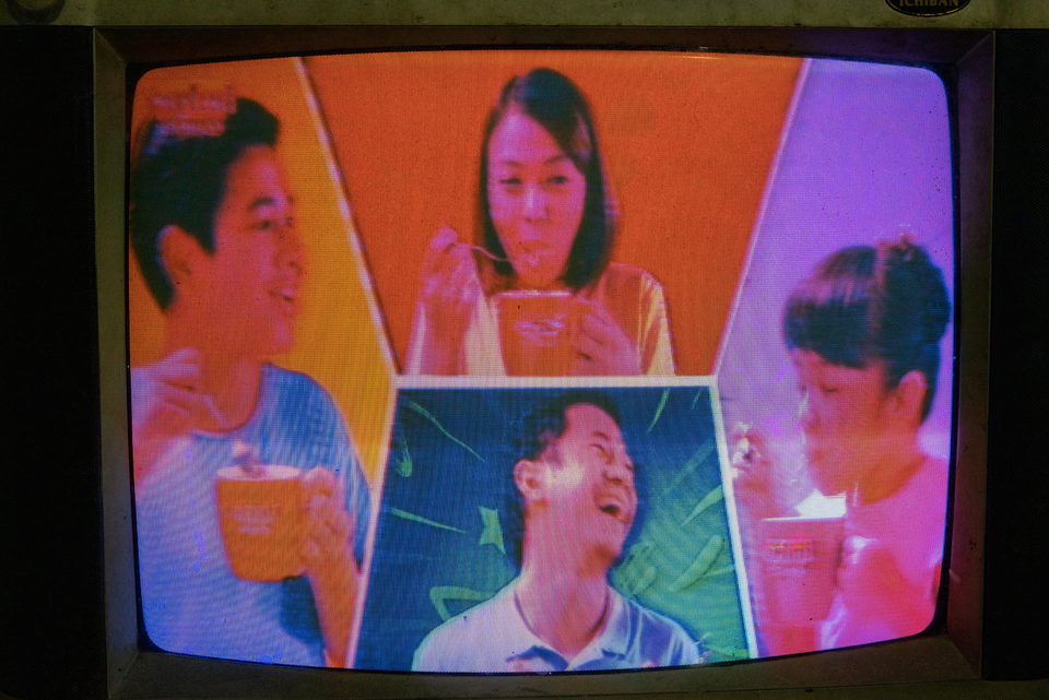 A television drama, faces around a table in saturated colour.