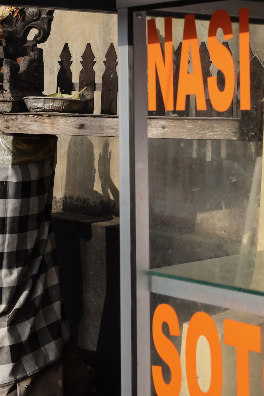 Orange NASI lettering above a stall counter and checked cloth.