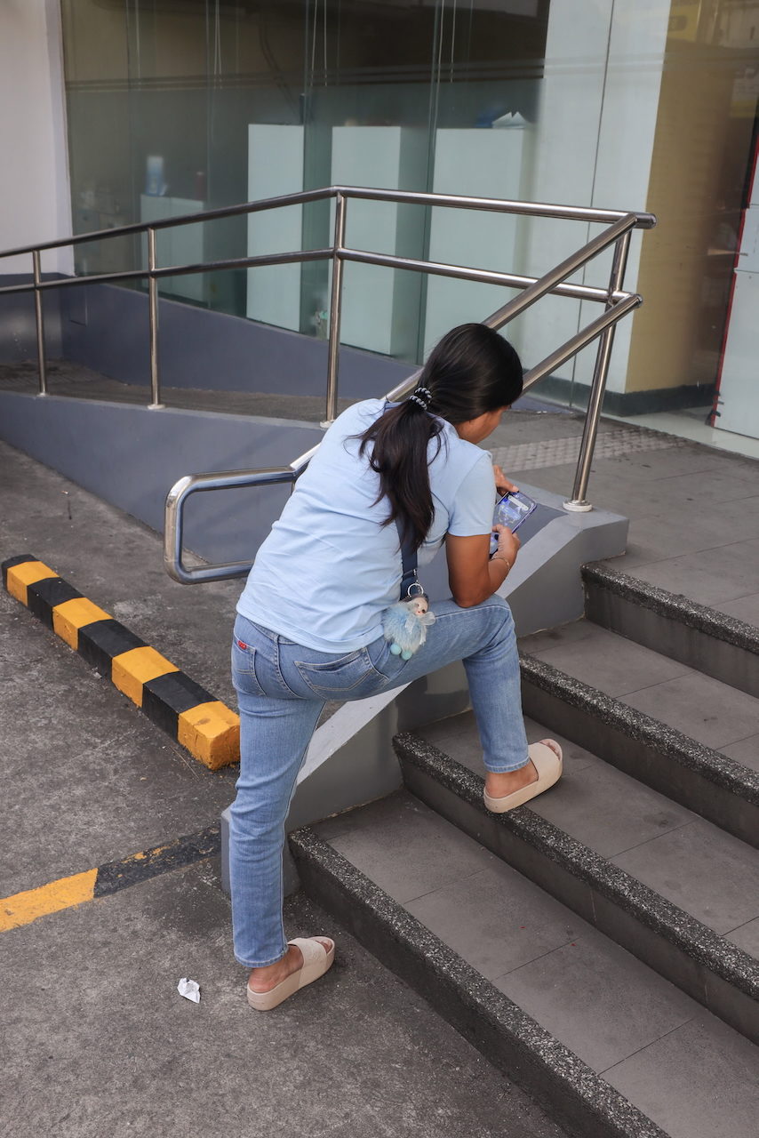 A woman sits on concrete steps looking at her phone.