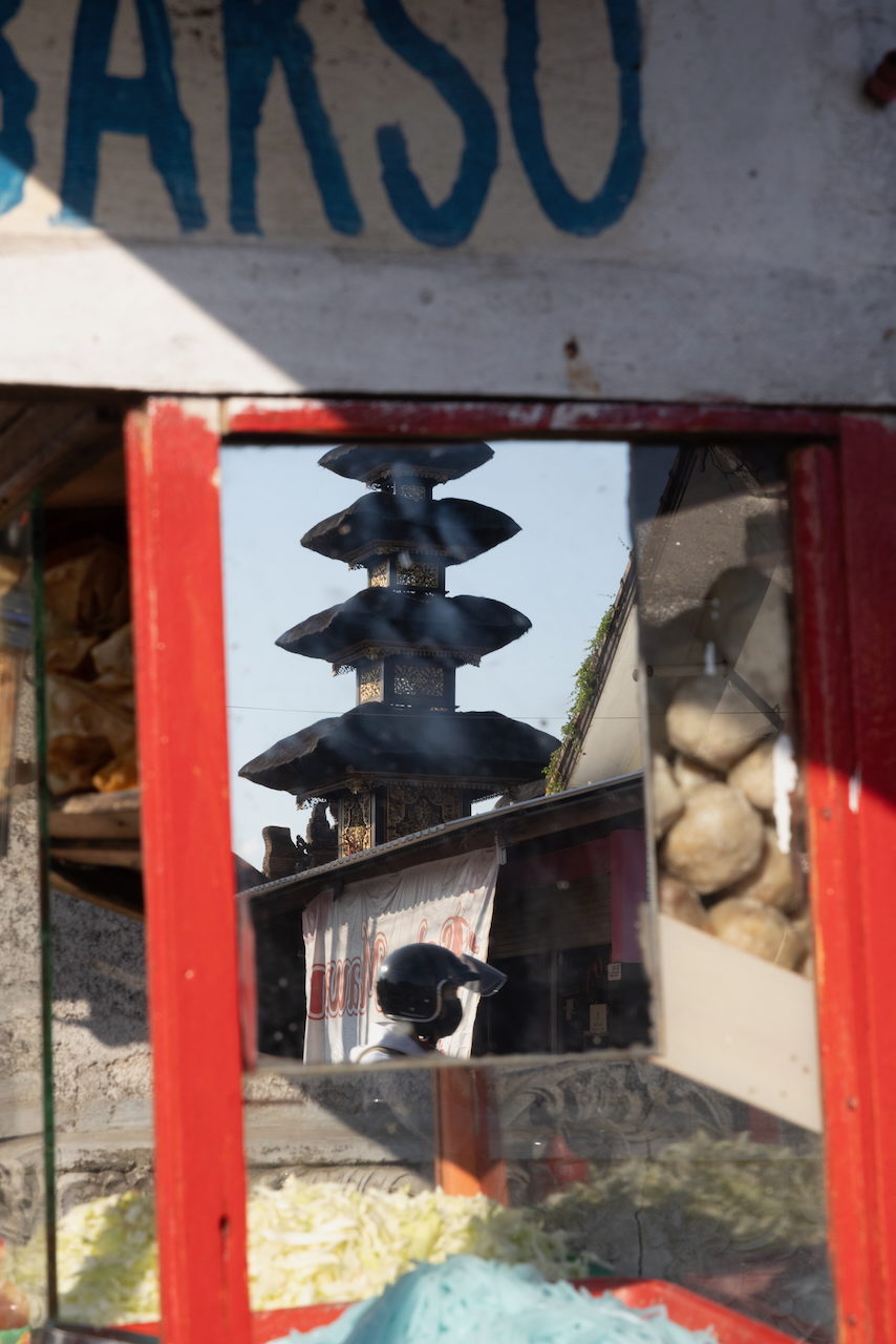 A black tiered ceremonial umbrella framed by a red cart window.