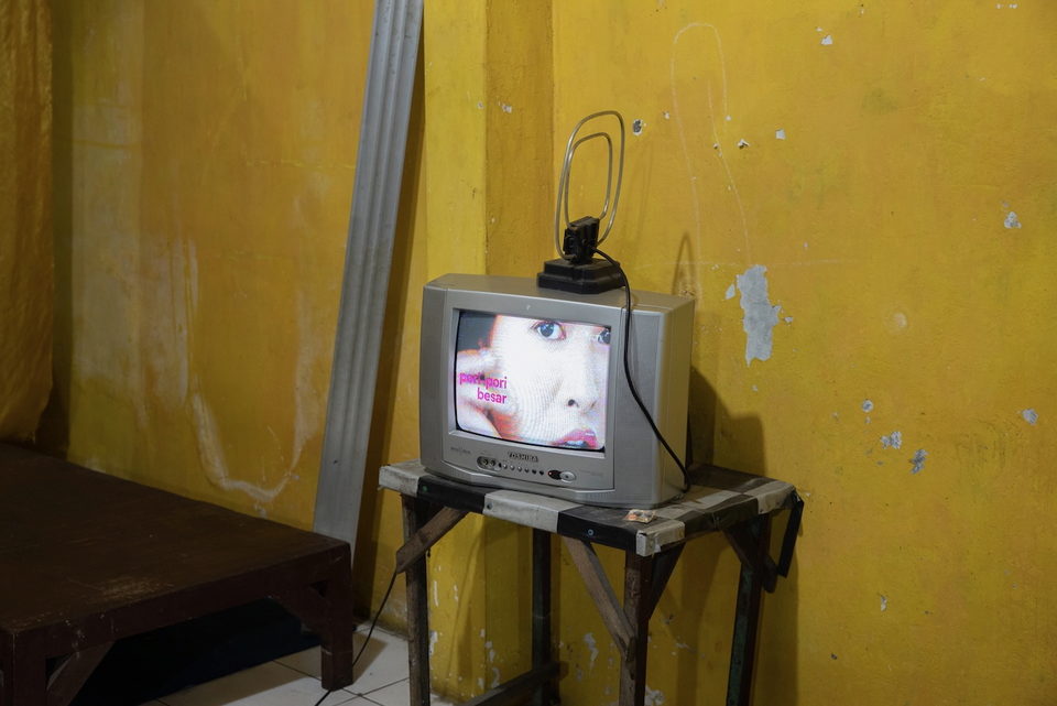 An old television on a wooden table against a yellow wall.