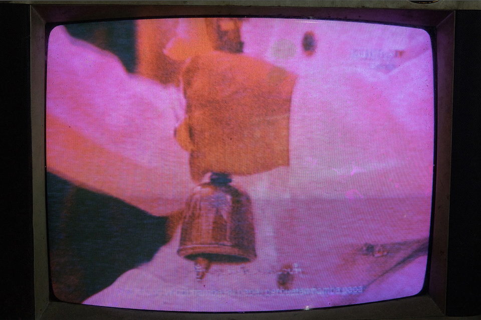 A television close-up washed pink, a bell in silhouette.