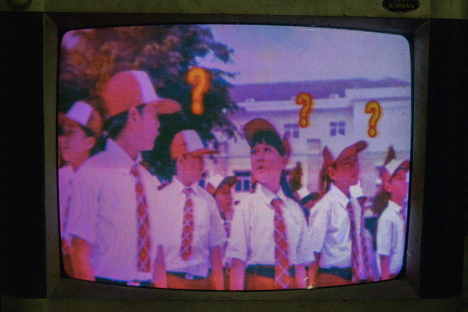 A television showing schoolchildren in uniform with question marks overlaid.