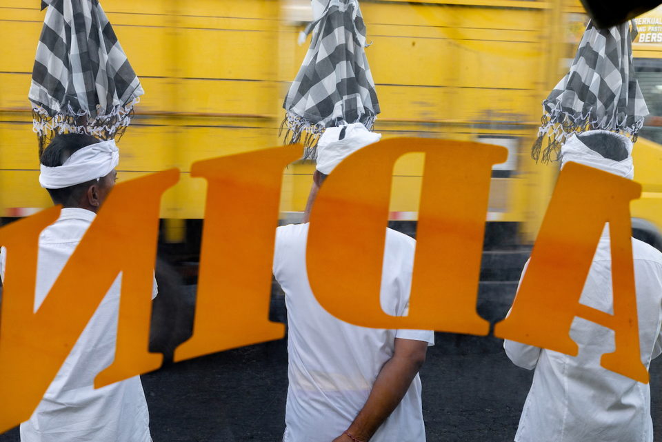 Large orange letters across the backs of men in white ceremonial dress.