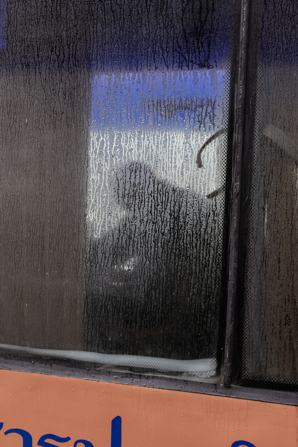 A silhouette behind a window streaked with condensation.