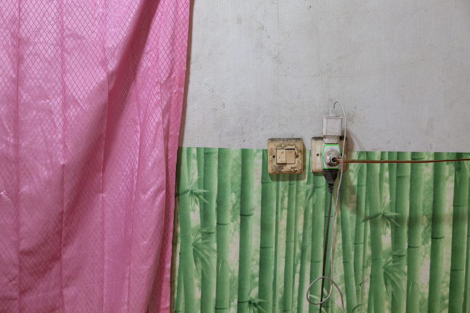 A pink curtain hangs beside a green bamboo-patterned wall and an electricity meter.
