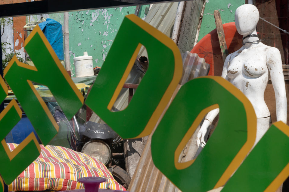 Green and gold lettering over a yard of corrugated iron, a white mannequin behind.