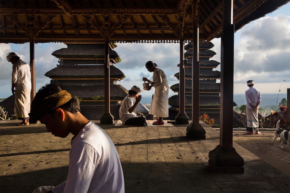 A priest tends offerings in a temple pavilion above the sea.