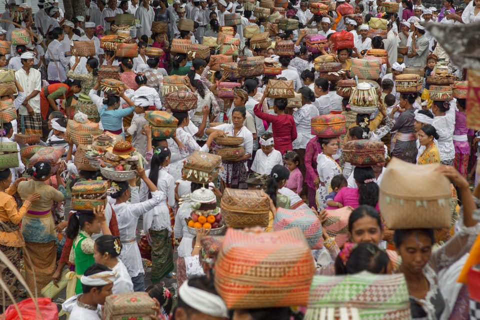 A dense crowd of women carrying tiered offerings on their heads at a ceremony.