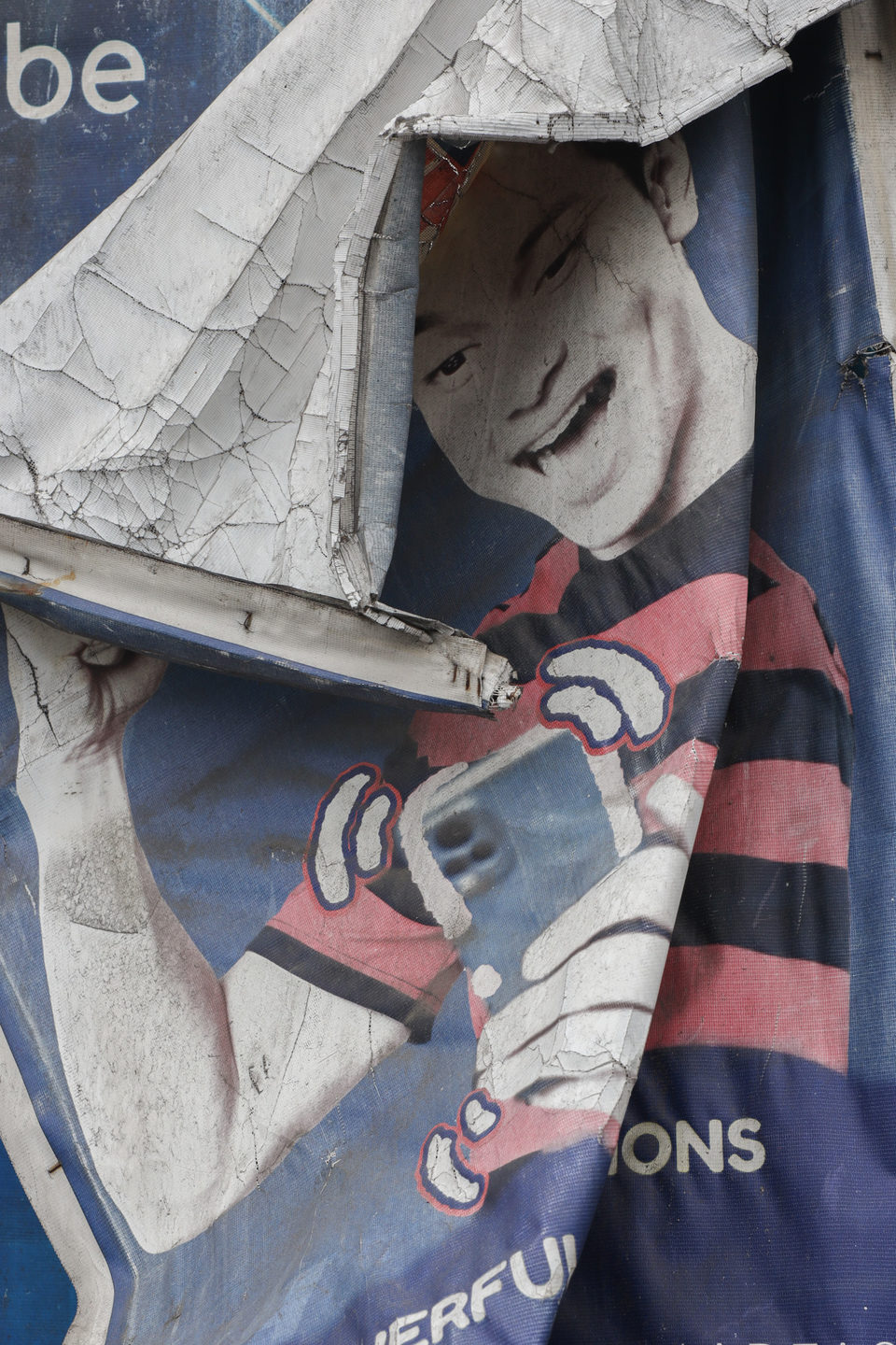 A torn poster showing a hand holding a phone.