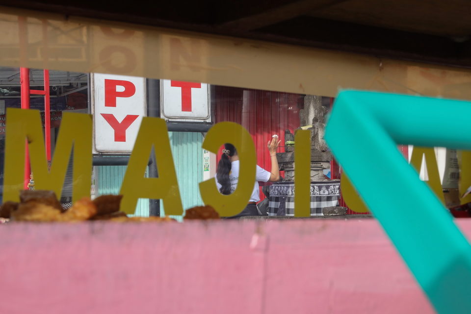 Pink and yellow lettering over a woman at a stall counter.