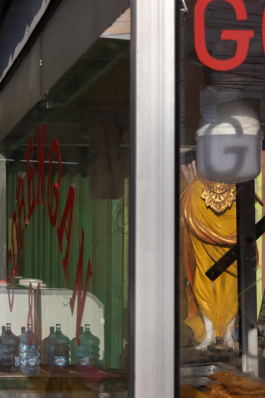 A gilded statue beside a green shopfront seen through the cart window.