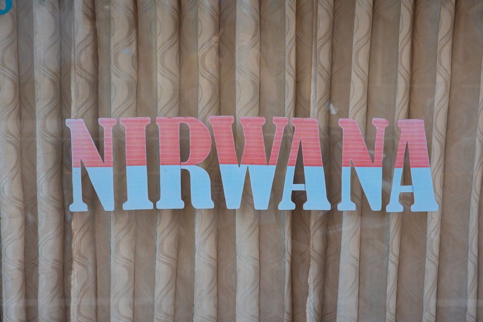 The word NIRWANA in pink and blue lettering across a corrugated wall.