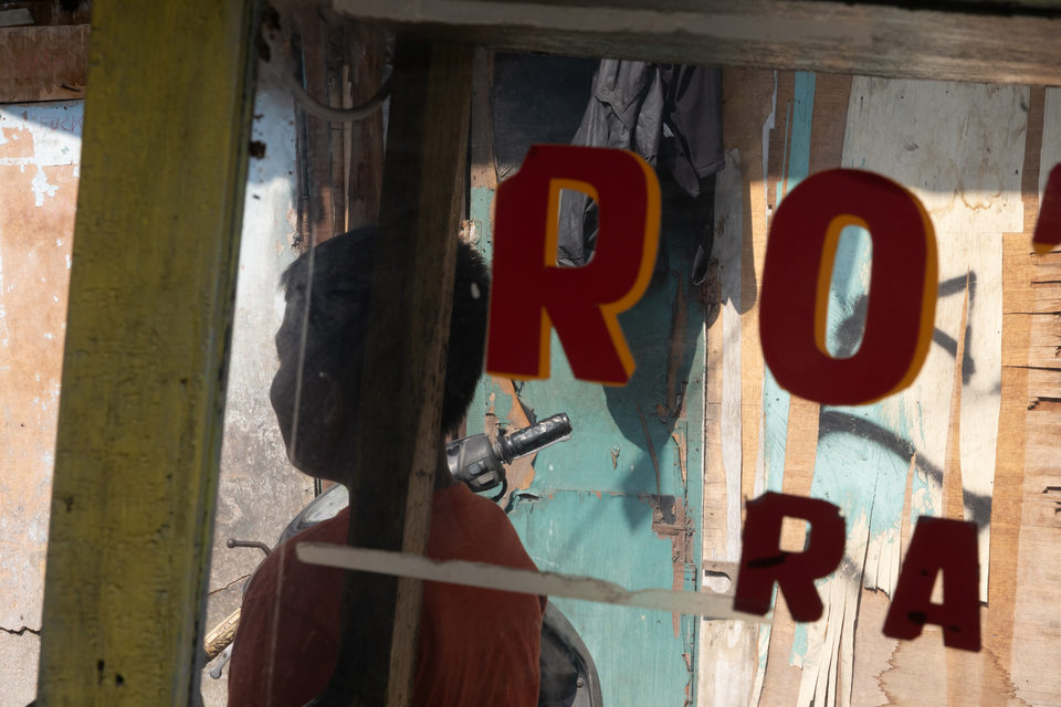 Dark red letters on the glass, a boy on a scooter against weathered timber.