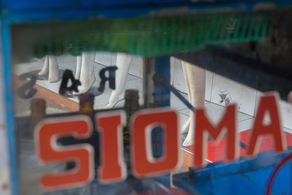 Red SIOM lettering over mannequin legs in a shop window.