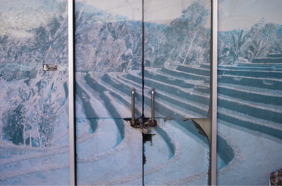 A mural of terraced rice fields painted across a pair of metal gates.