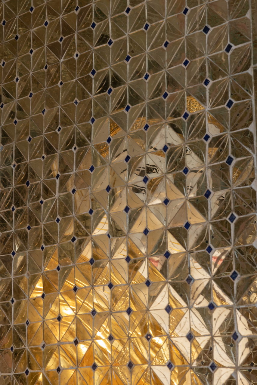 A wall of gold and mirrored glass tiles set in a diamond lattice.