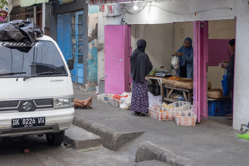 A street stall lit pink, a woman standing at the counter.