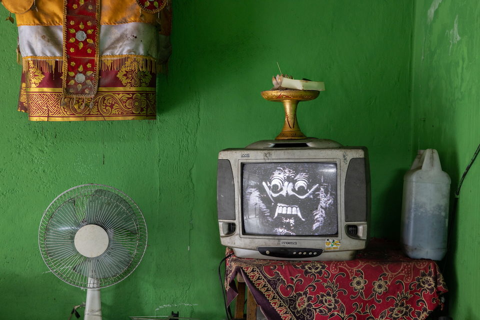 An old television with a lamp on top against a bright green wall.