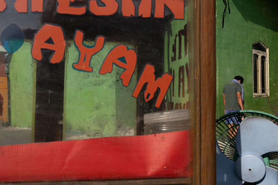 Red and orange lettering across the glass of a chicken stall.