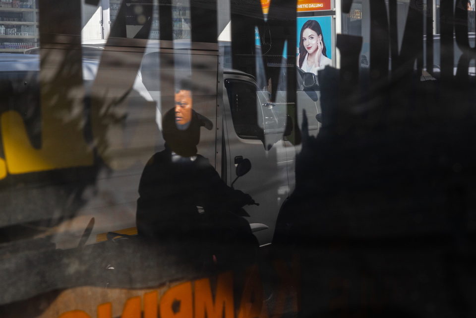 Figures reflected in dark glass above red lettering.