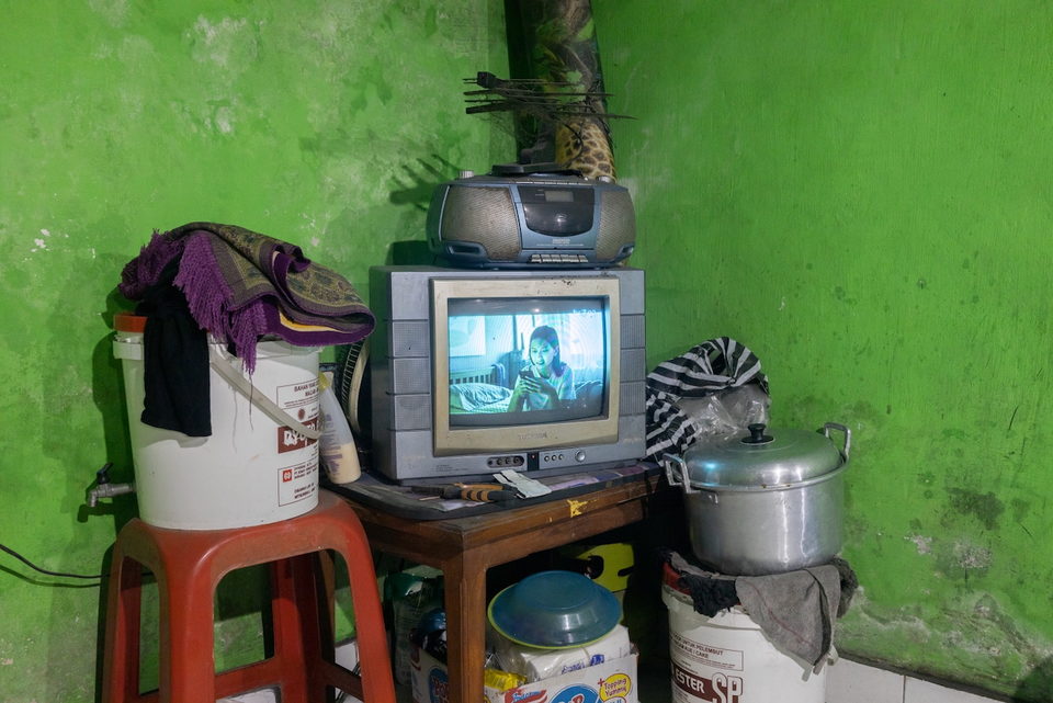 A television and stereo on a table beside cooking pots.